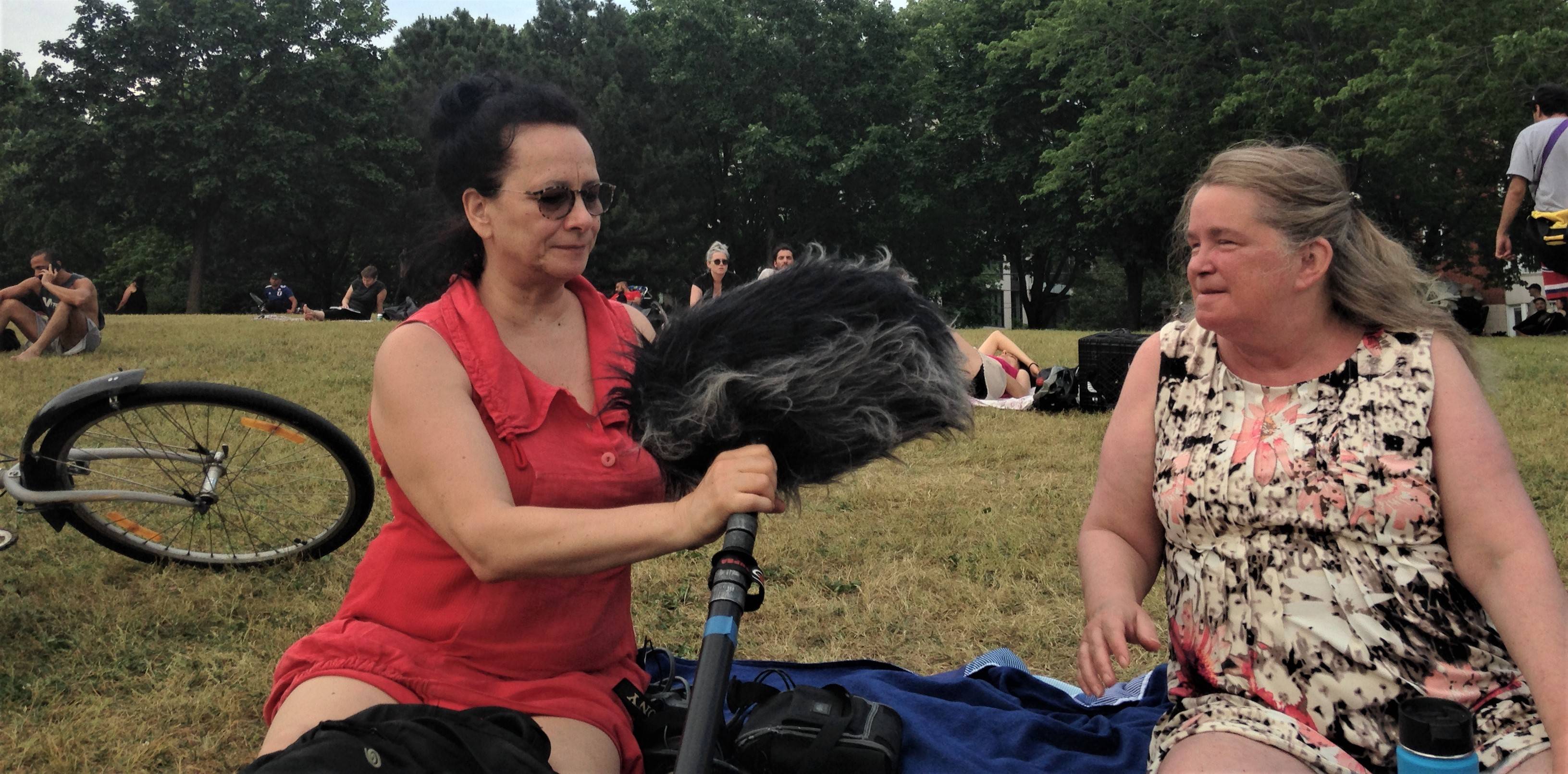 Chantal Dumas et Josée Boyer assises au Parc Jarry. Chantal tend un micro à Josée