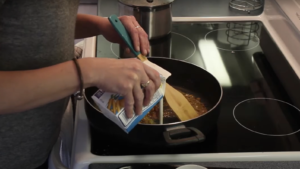 Photo de Tanya qui cuisine et qui verse de la crème dans une poêle.