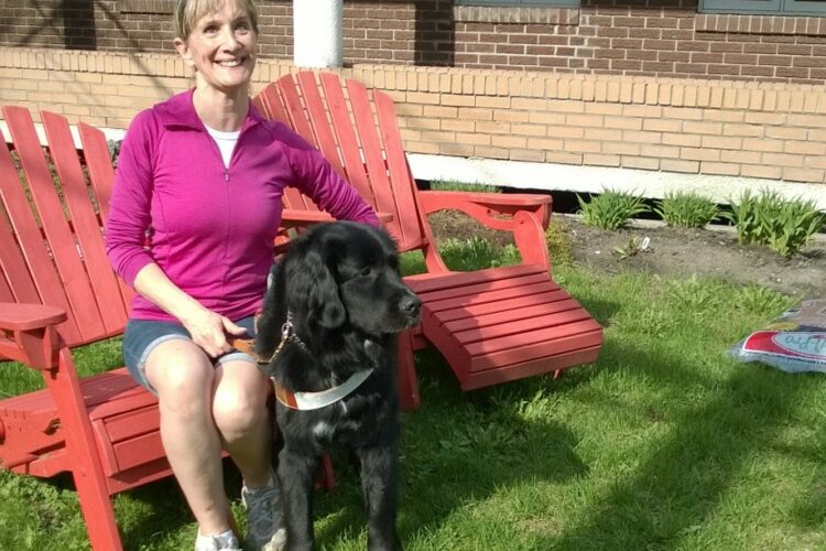 Photo de France Poulin assise à l'extérieur avec son chien-guide Onyx